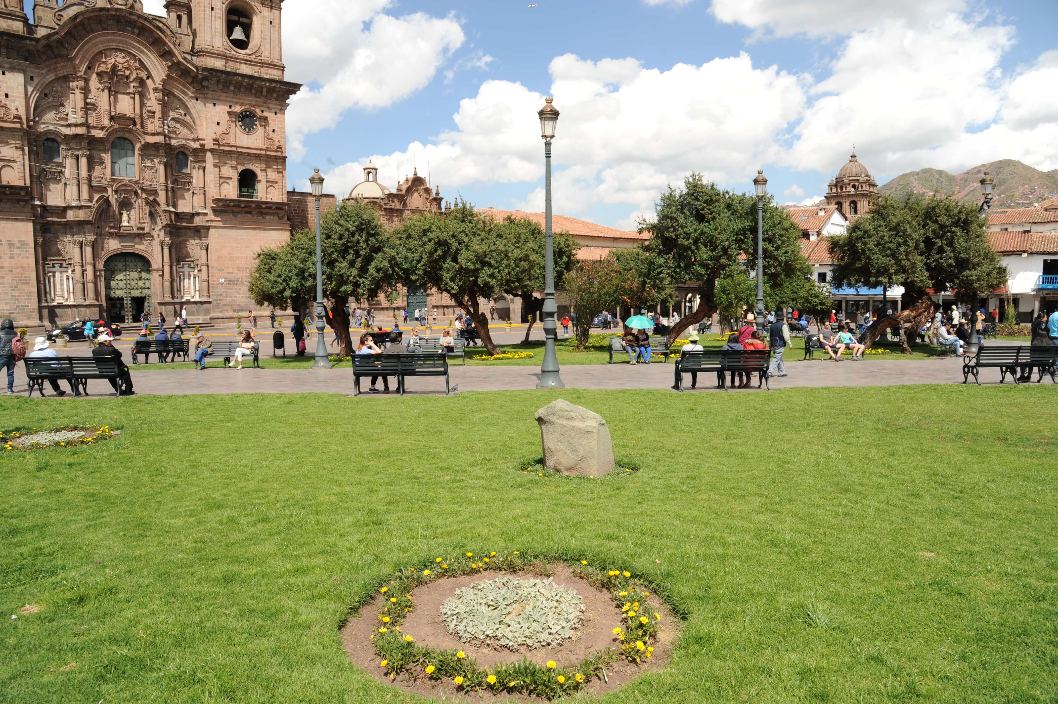 Sunny skies shine over Cusco's Plaza de Armas, where benches and gardens invite a moment of rest. 