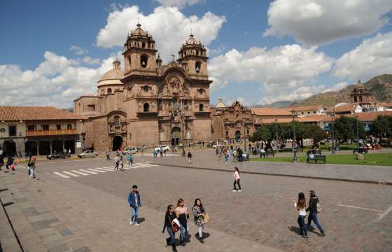 Locals and travelers gather in Cusco's vibrant Plaza de Armas, framed by baroque colonial churches. 
