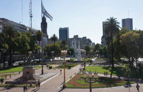 Plaza de Mayo, the political and historical heart of Buenos Aires, surrounded by palm trees, colonial architecture, and government buildings. 