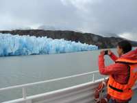 A tourist captures a photo of a brilliant blue glacier from the deck of a boat in Chile's Torres del Paine National Park. 