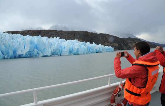 A tourist captures a photo of a brilliant blue glacier from the deck of a boat in Chile's Torres del Paine National Park. 