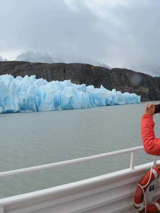 A tourist captures a photo of a brilliant blue glacier from the deck of a boat in Chile's Torres del Paine National Park. 