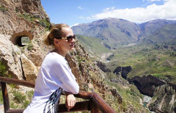 A traveler gazes across Colca Canyon's vast expanse, surrounded by dramatic peaks and clear skies. 