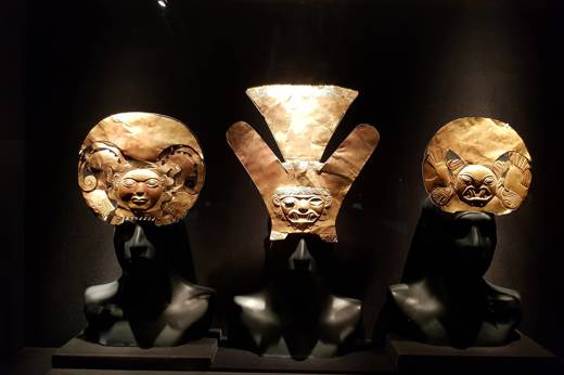 Ancient gold masks and ceremonial artifacts on display in a lima museum exhibit. 
