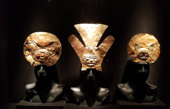 Ancient gold masks and ceremonial artifacts on display in a lima museum exhibit. 