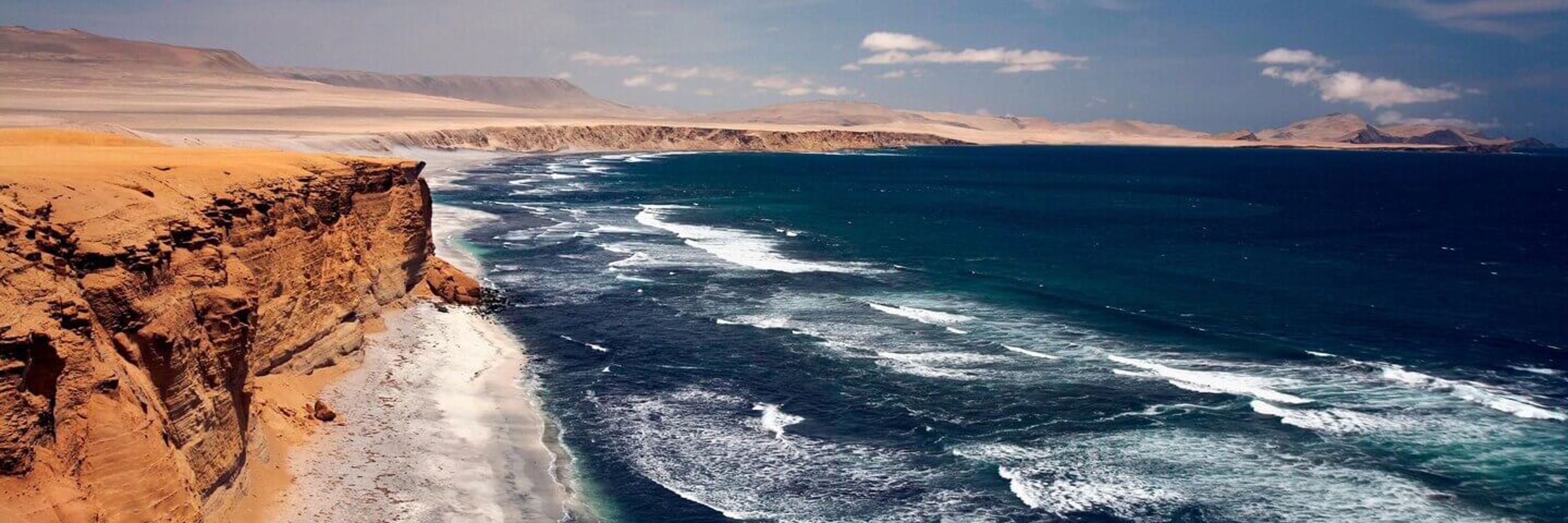 View from Mirador La Catedral in Paracas Reserve, with rugged cliffs and waves along Peru's Pacific coast. 