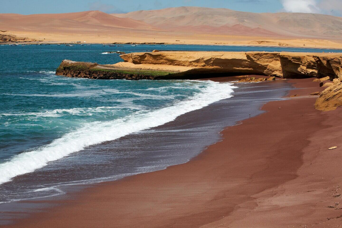 Red Beach in Paracas Reserve, where vibrant red sands meet turquoise waters along Peru's dramatic coast. 