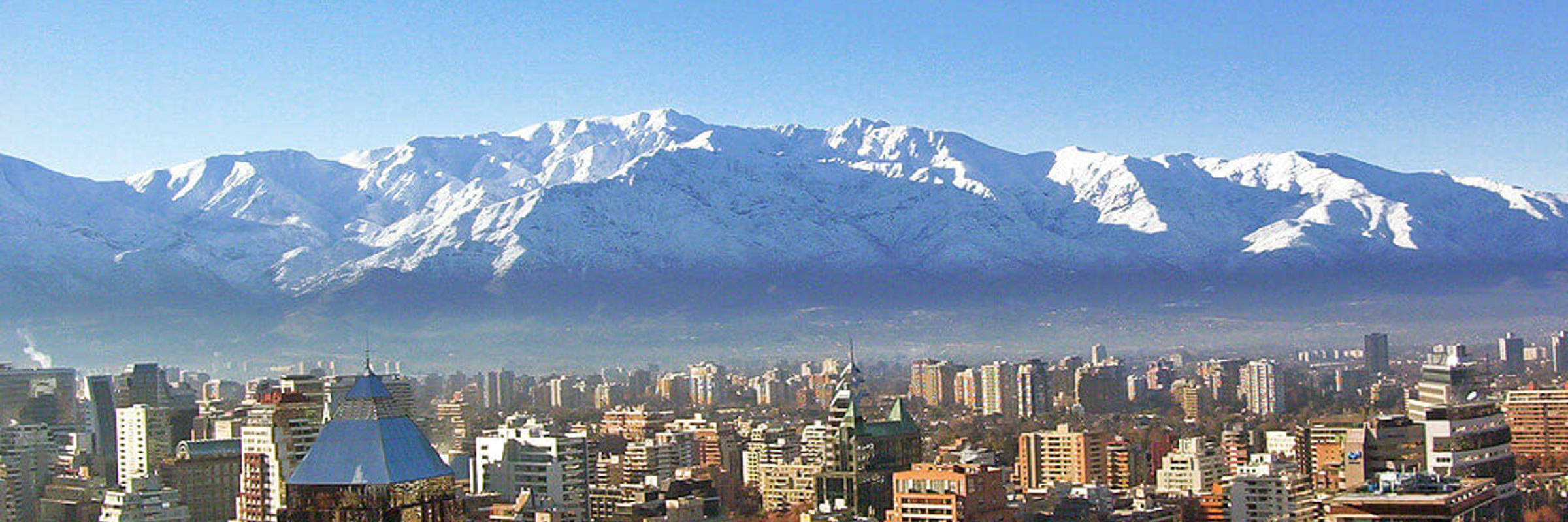 Snow-covered Andes towering above Santiago's urban skyline on a crisp winter day in central Chile. 