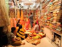India- Women shopping for colourful saris in a traditional fabric store full of vibrant textiles. 