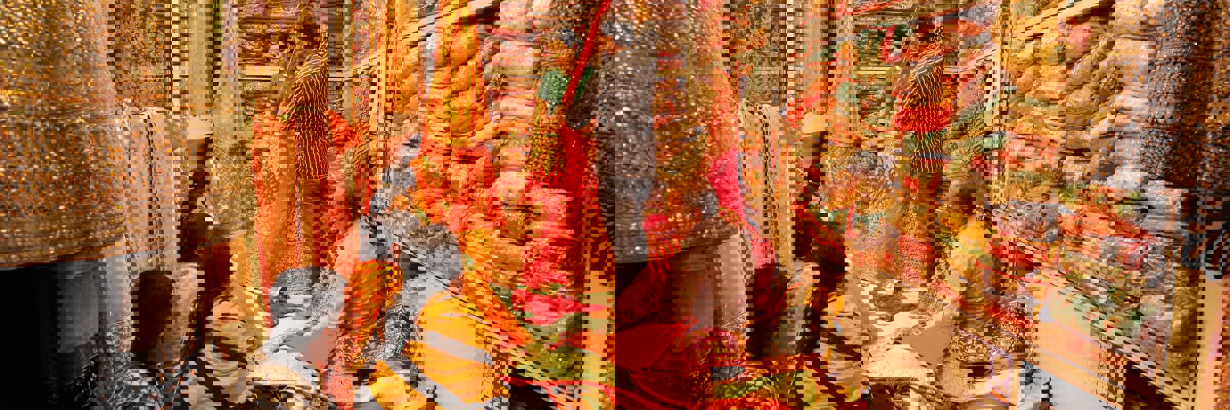 India- Women shopping for colourful saris in a traditional fabric store full of vibrant textiles. 