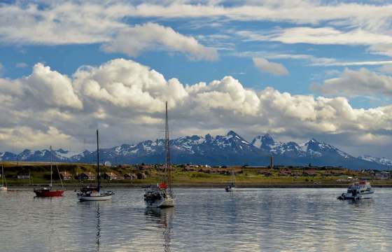 Sailboats float peacefully in Ushuaia's Beagle Channel with Patagonia's peaks behind. 
