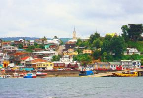 Colorful houses line the harbor of Castro on Chiloe Island, Chile, showcasing the island's iconic coastal charm and fishing culture. 
