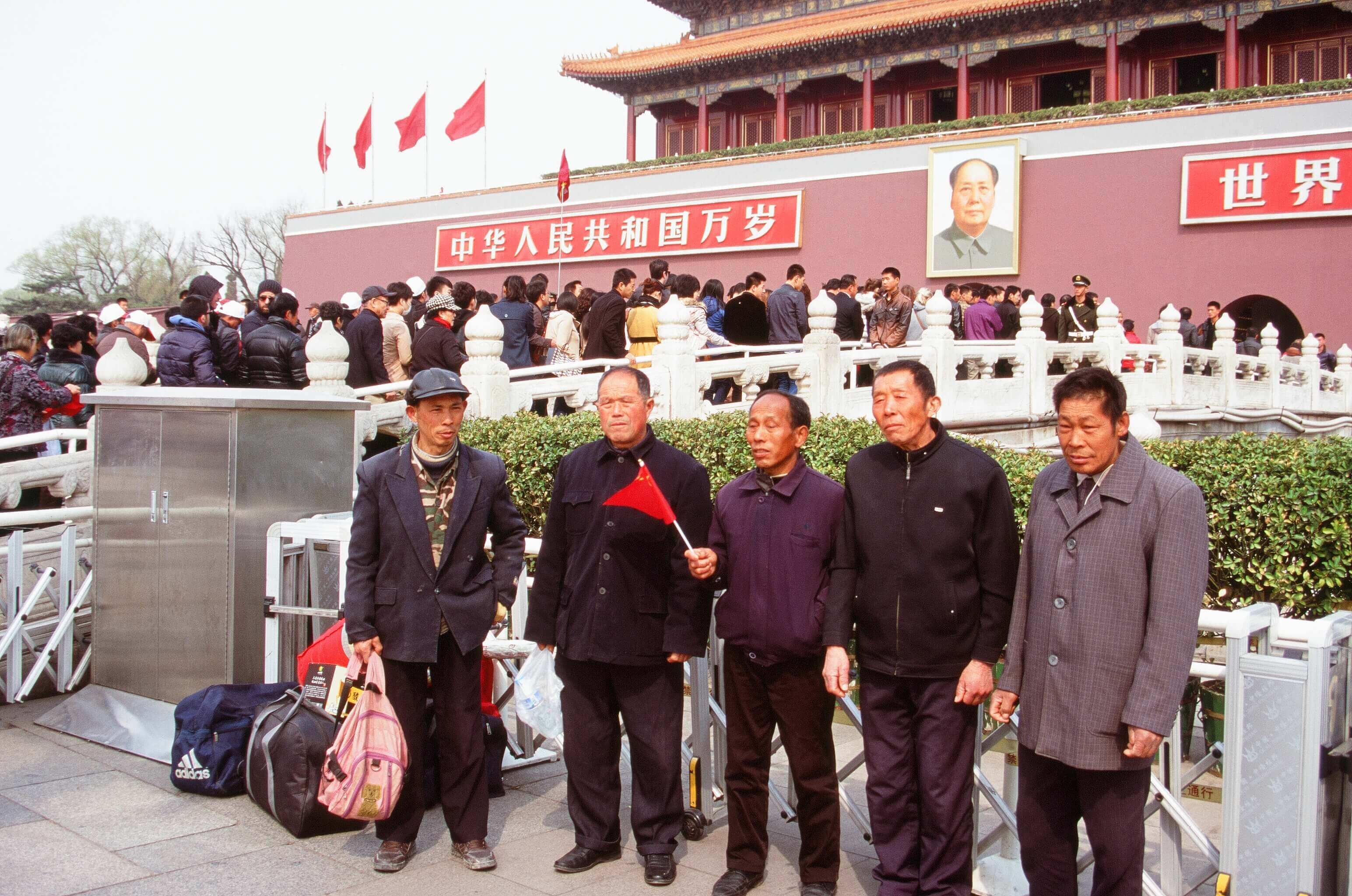 China- Group of men pose at Tiananmen Square, Beijing, in front o Mao's portrait at this iconic historic site. 
