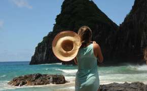 Woman with sunhat overlooks ocean and cliffs at Fernando de Noronha, a stunning island destination in Brazil. 
