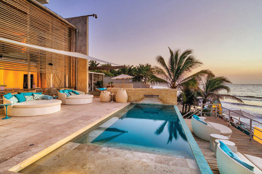 Stylish resort pool and palm-lined terrace overlooking the beach in sunny Mancora, Peru. 