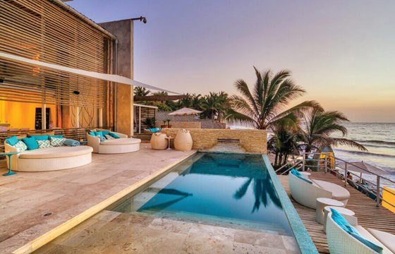 Stylish resort pool and palm-lined terrace overlooking the beach in sunny Mancora, Peru. 