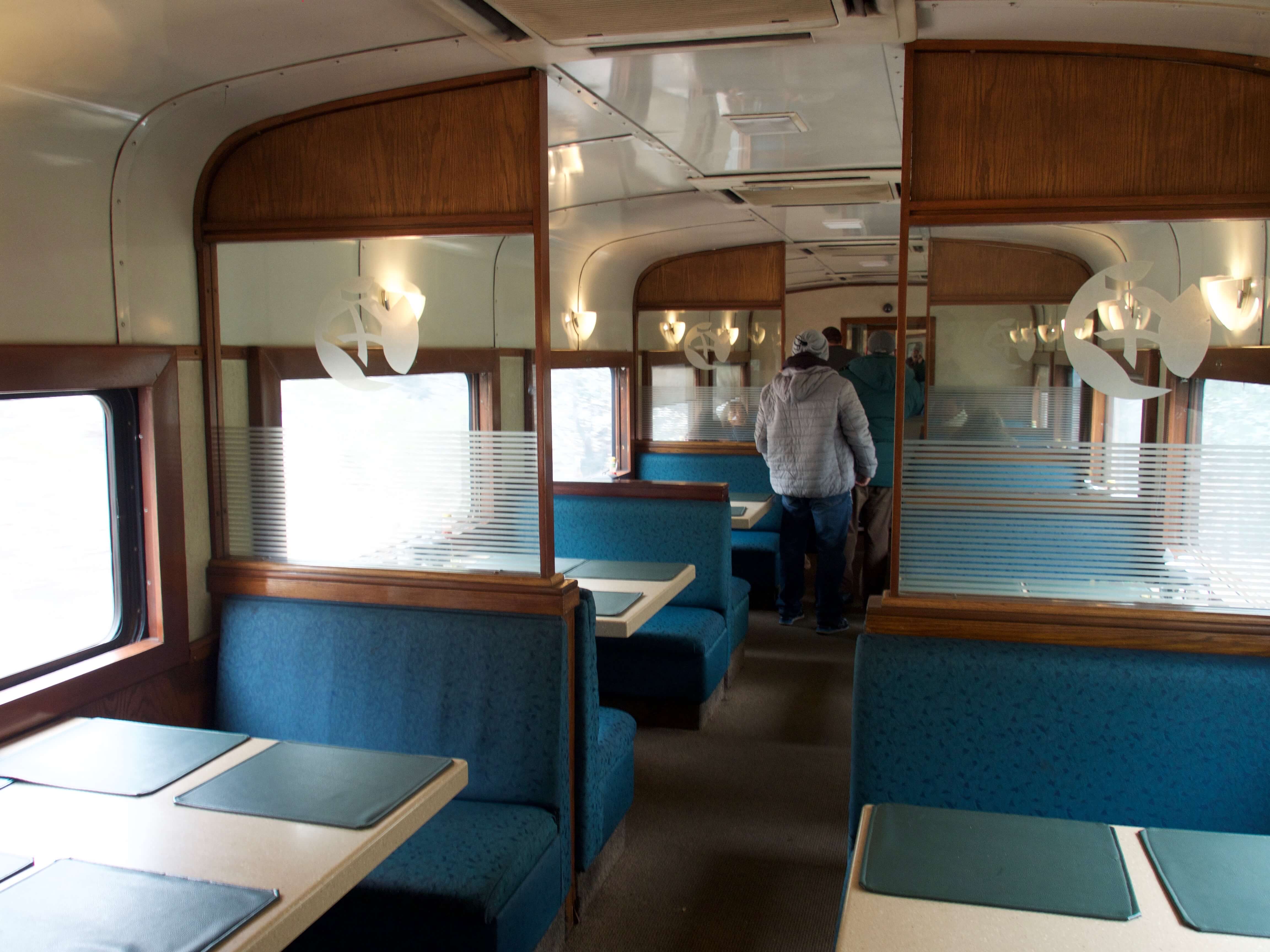 Interior of the dining car on the Chepe Train with turquoise booths and panoramic windows through Mexico's Copper Canyon. 