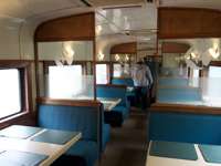 Interior of the dining car on the Chepe Train with turquoise booths and panoramic windows through Mexico's Copper Canyon. 