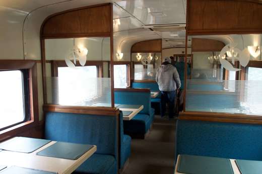 Interior of the dining car on the Chepe Train with turquoise booths and panoramic windows through Mexico's Copper Canyon. 