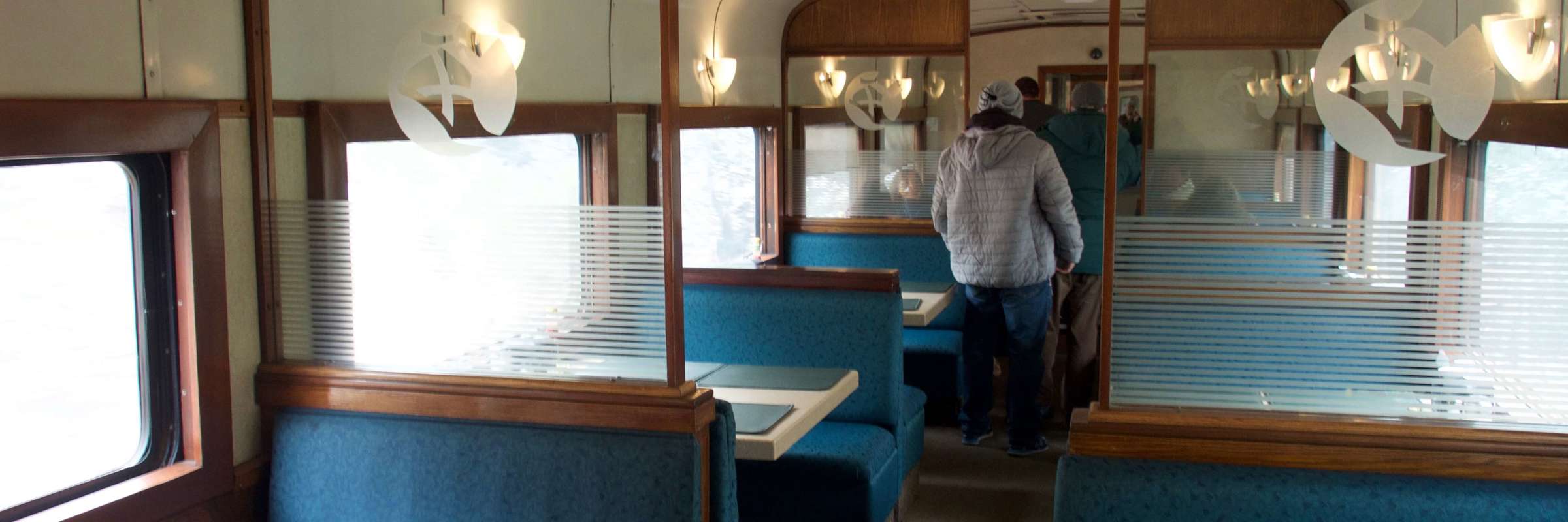 Interior of the dining car on the Chepe Train with turquoise booths and panoramic windows through Mexico's Copper Canyon. 