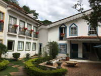 Colonial courtyard hotel with balconies and flower boxes in Minas Gerais, Brazil, featuring a peaceful garden setting. 