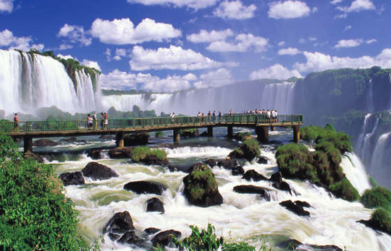 Visitors walk the boardwalk at Iguassu Falls, Brazil, surrounded by thunderous waterfalls. 