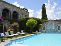 Outdoor pool at Casa de Sierra Nevada in San Miguel de Allende, Mexico, surrounded by stone walls, gardens, and sun loungers. 