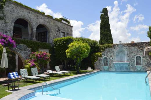 Outdoor pool at Casa de Sierra Nevada in San Miguel de Allende, Mexico, surrounded by stone walls, gardens, and sun loungers. 