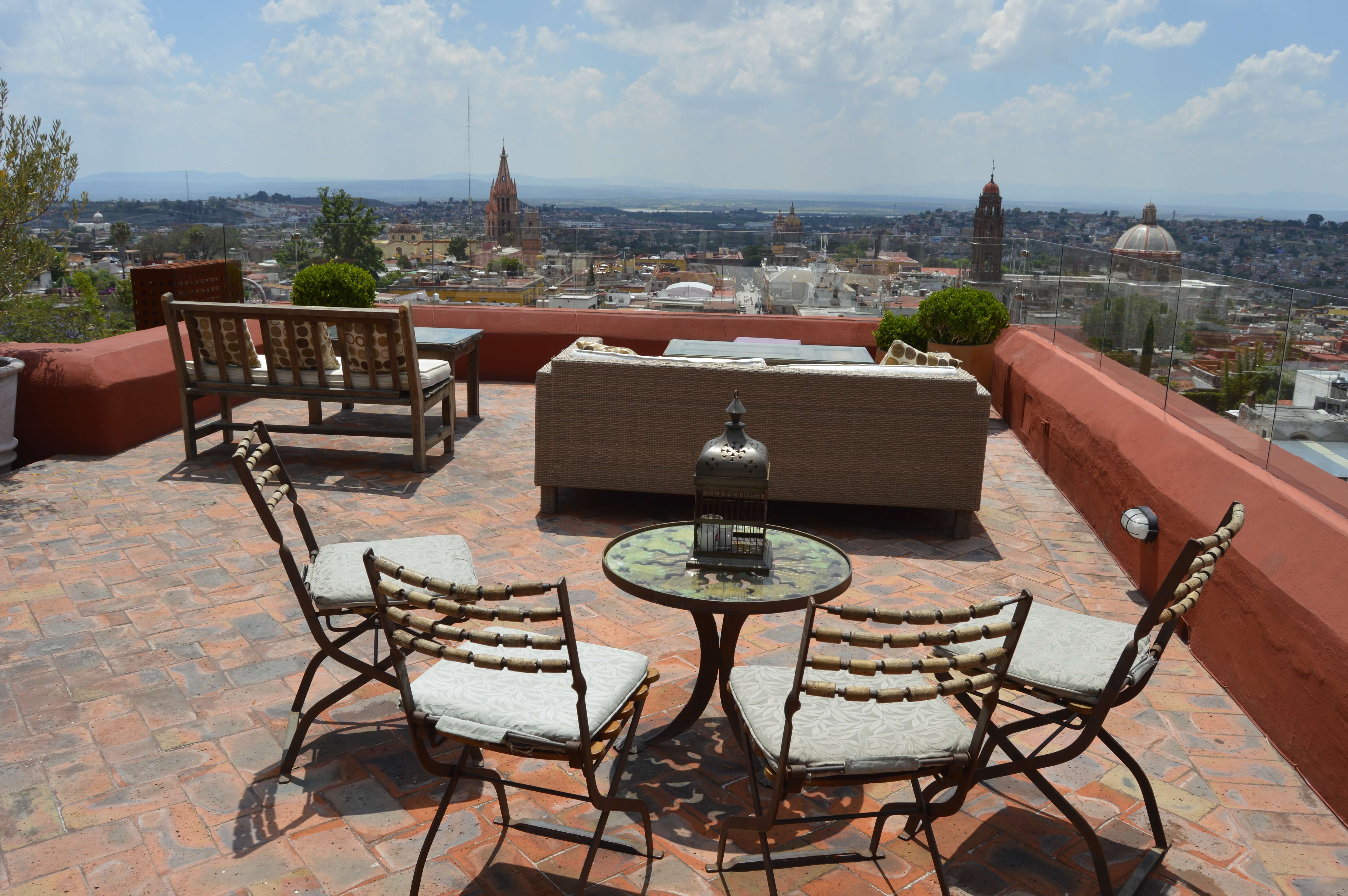 Terrace view over San Miguel de Allende, Mexico, with patio chairs and  a cityscape featuring church domes and skyline. 