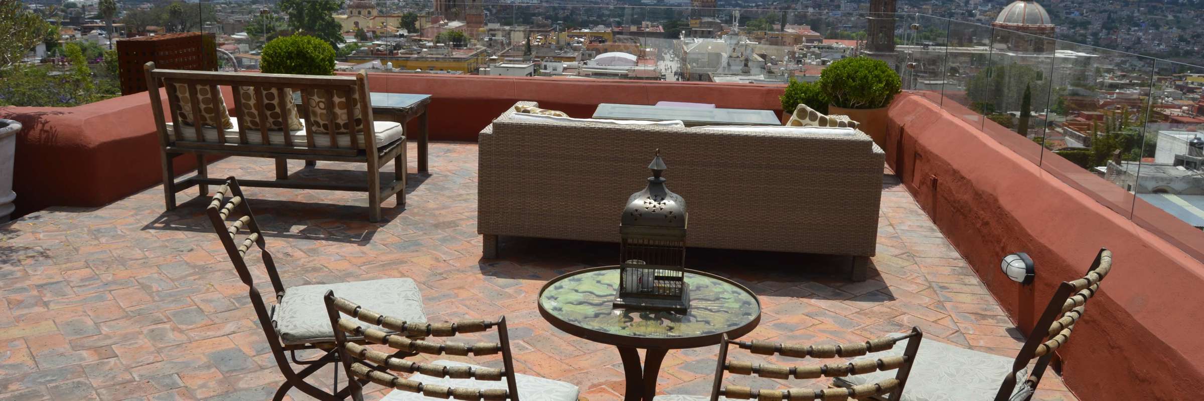 Terrace view over San Miguel de Allende, Mexico, with patio chairs and  a cityscape featuring church domes and skyline. 
