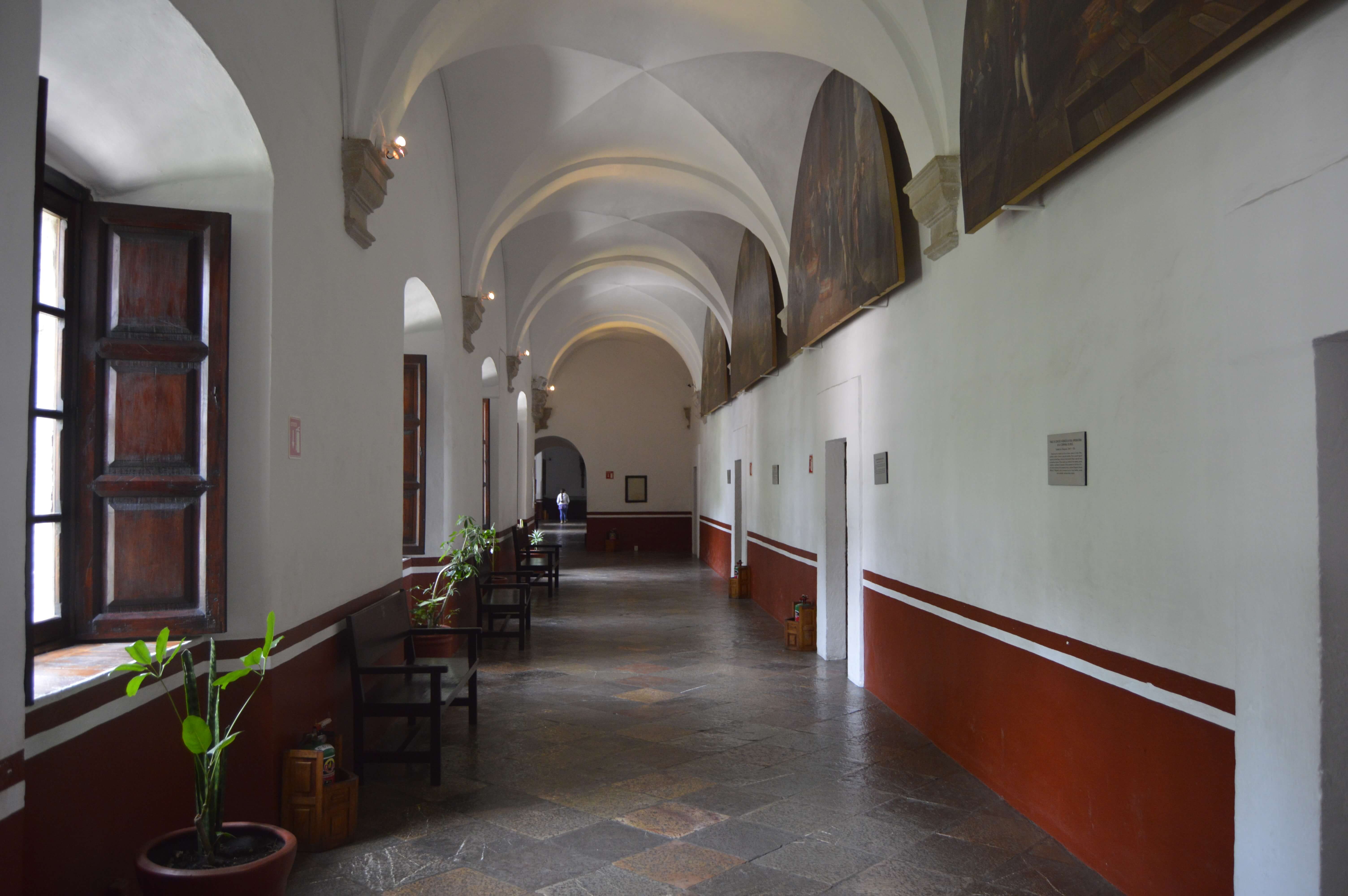 Colonial-style arched corridor with benches and potted plants inside a historic buildings in San Miguel de Allende, Mexico. 