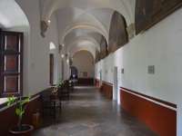 Colonial-style arched corridor with benches and potted plants inside a historic buildings in San Miguel de Allende, Mexico. 