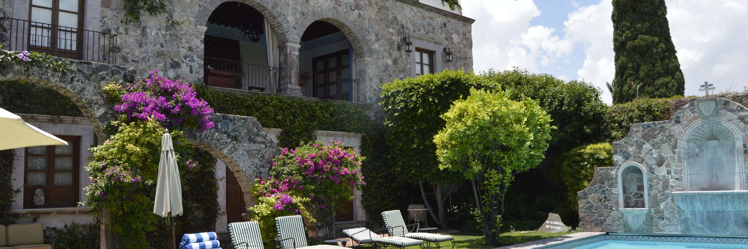 Outdoor swimming pool with sun loungers, stone arches, and gardens at a boutique hotel in San Miguel de Allende, Mexico. 