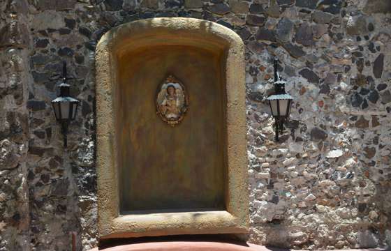 Decorative Virgin Mary niche in a stone wall with lanterns, typical colonial detail in San Miguel de Allende, Mexico. 