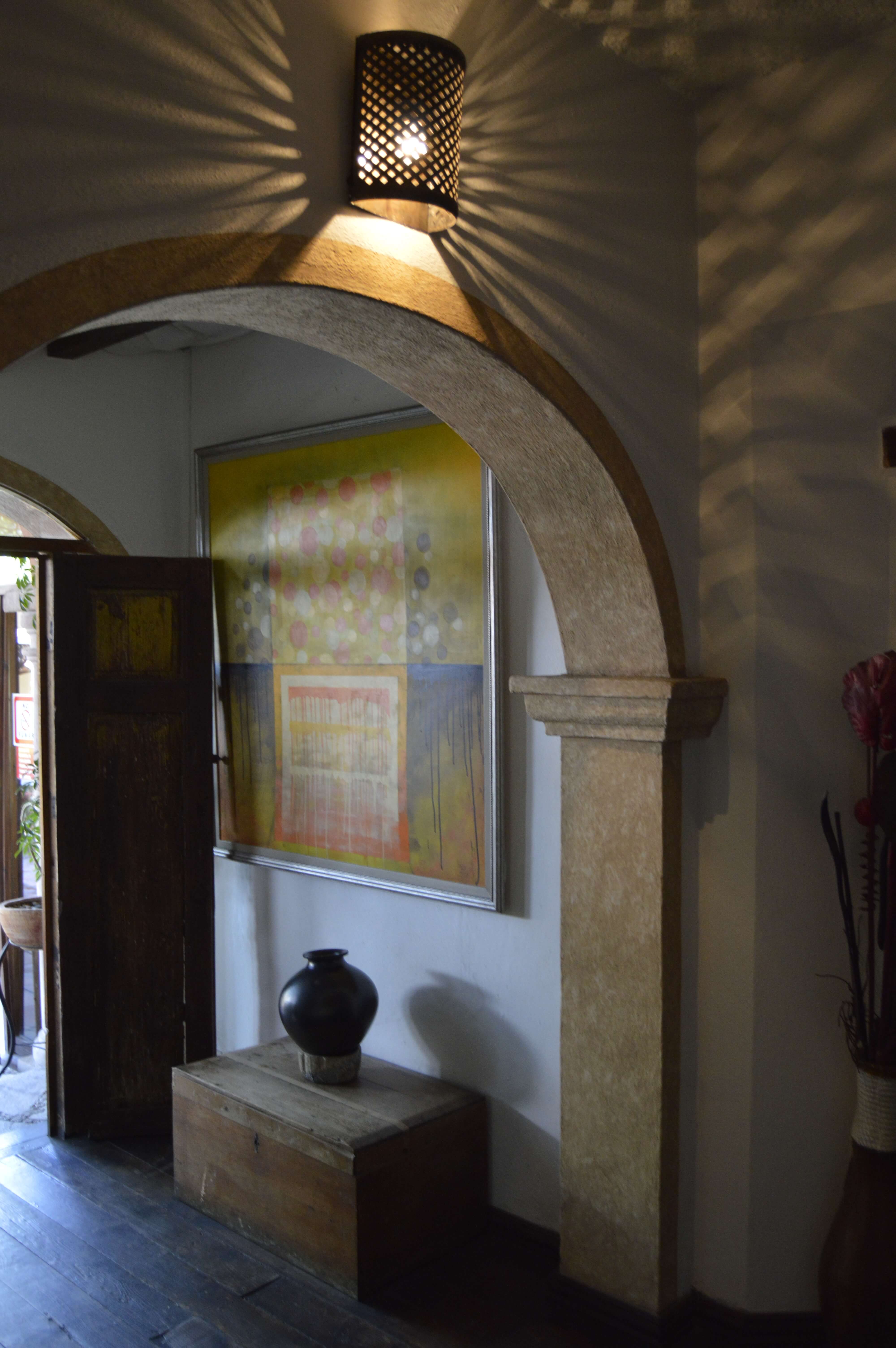 Rustic stone archway with wooden door, jar, and patterned lighting inside a boutique hotel in San Miguel de Allende, Mexico. 
