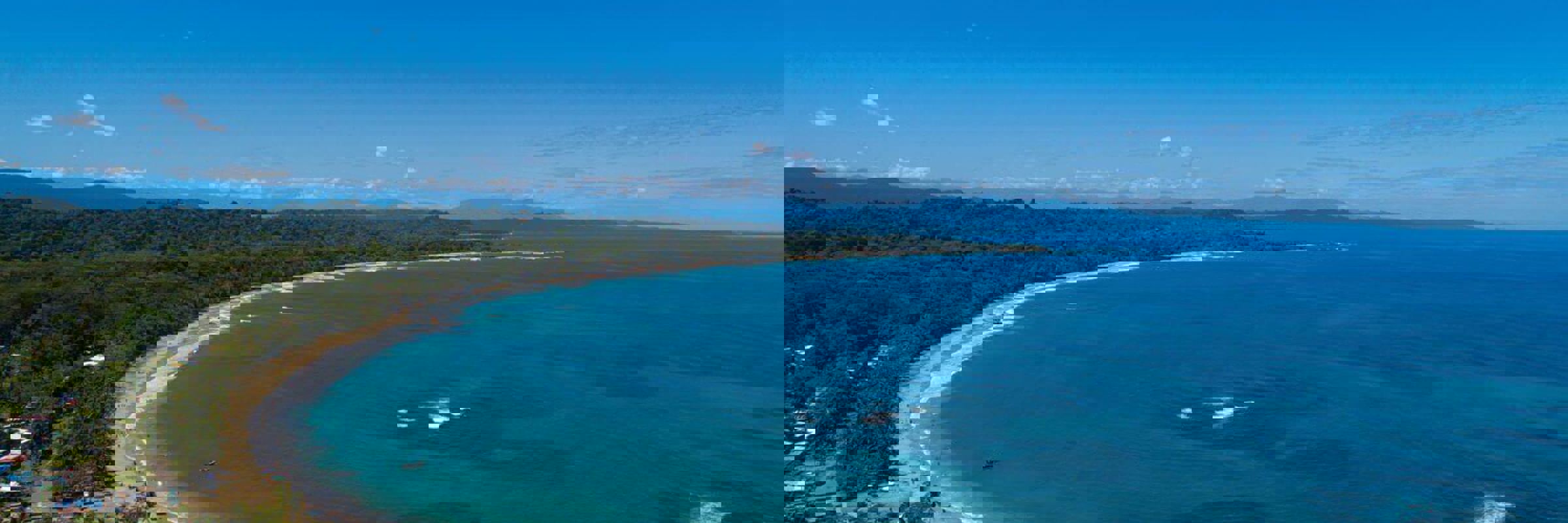 An aerial view of the sweeping Caribbean shoreline at Le Cameleon near Puerto Viejo, edged by lush rainforest. 