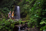 Couple hiking through lush rainforest to a hidden waterfall in Costa Rica's Tenorio National Park. 