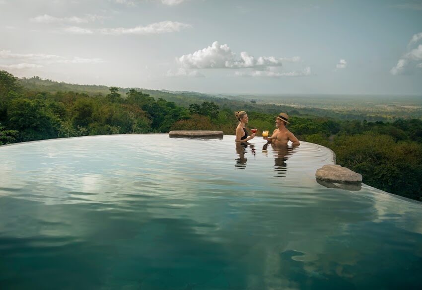 Guests relax in the infinity pool at Origins Lodge, overlooking lush mountains in northern Costa Rica. 