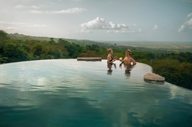 Guests relax in the infinity pool at Origins Lodge, overlooking lush mountains in northern Costa Rica. 
