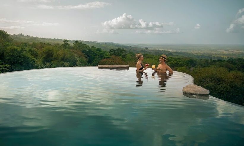 Guests relax in the infinity pool at Origins Lodge, overlooking lush mountains in northern Costa Rica. 