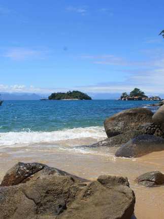 Small boat anchored off a secluded beach with rocky shoreline on Ilha Grande. 