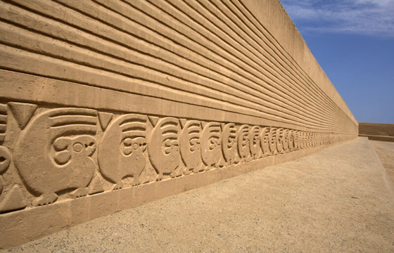 Intricate adobe carvings stretch along Chan Chan's ancient walls under Peru's desert sun. 