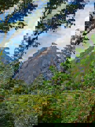 Arenal Volcano rises majestically beyond the treetops, framed by lush Costa Rican greenery. 