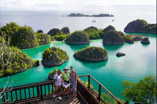 Tourists admire the iconic karst islands of Piaynemo from a scenic wooden lookout in Raja Ampat, West Papua, Indonesia. 