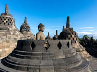 A Buddha statue sits in quiet stillness among stupas at Borobudur Temple in Central Java, Indonesia. 