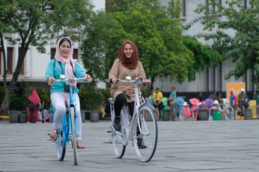 Women enjoying cycling in Jakarta's Old Town, promoting inclusive tourism experience in Indonesia's capital. 