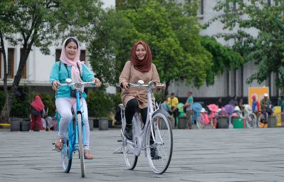 Women enjoying cycling in Jakarta's Old Town, promoting inclusive tourism experience in Indonesia's capital. 