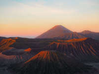 Mount Bromo and surrounding caldera at sunrise in East Java, Indonesia, with soft morning light and volcanic landscape. 