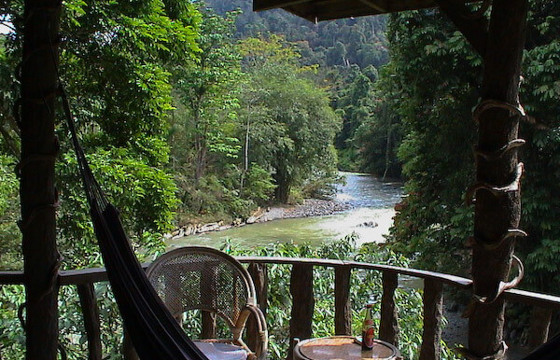 Peaceful jungle lodge balcony with hammock and chairs overlooking a tropical river in Sumatra, Indonesia. 