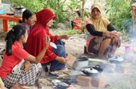 Local women in Bukit Lawang prepare a traditional Indonesian meal over an open fire, showcasing authentic village fire. 